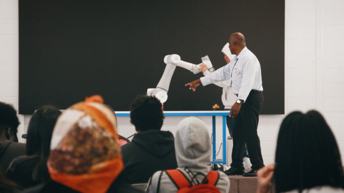 Electrical Technology Instructor Lardell Goodloe demonstrating a robotic arm